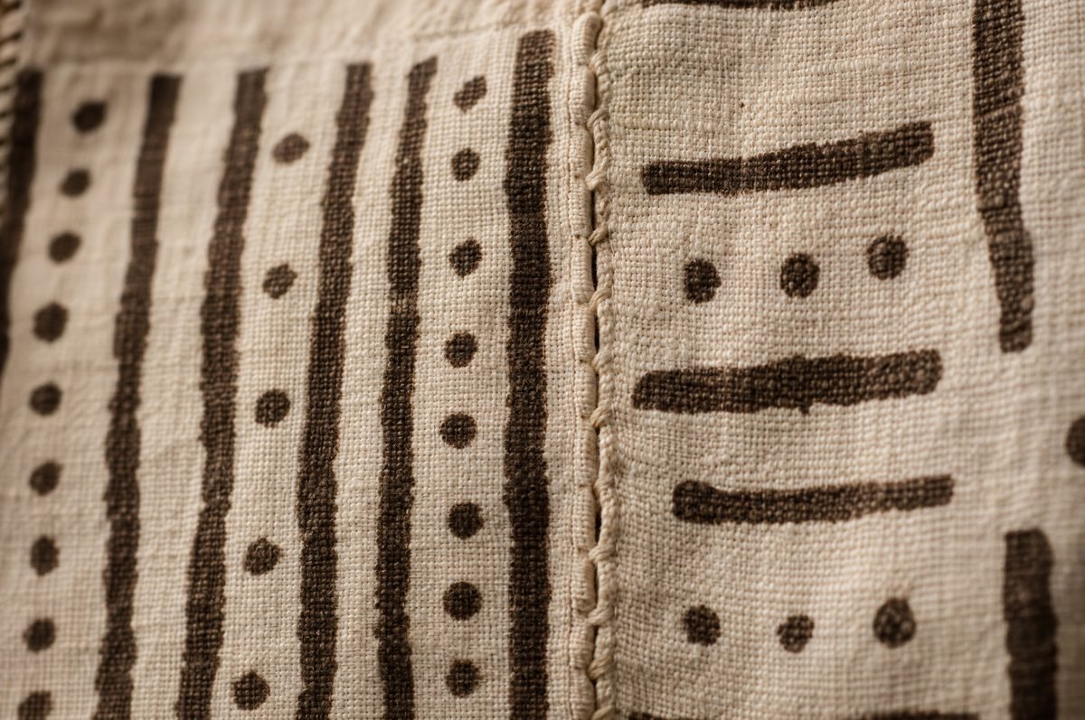 Close-up of a mud cloth seam where two handwoven cotton strips meet, with hand-drawn brown lines and dots